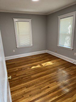 A room with wooden floors and two windows.