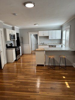 A kitchen with wooden floors and white cabinets.