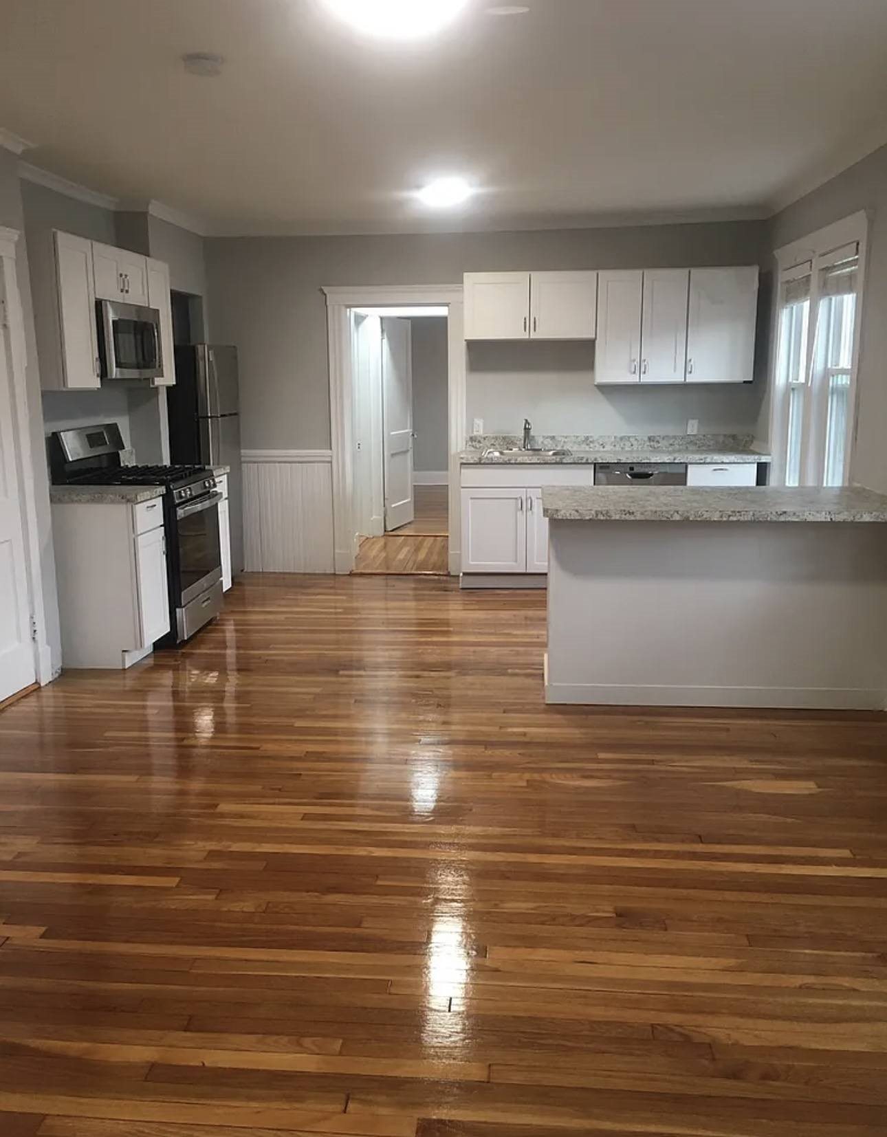 A kitchen with white cabinets and a wooden floor.