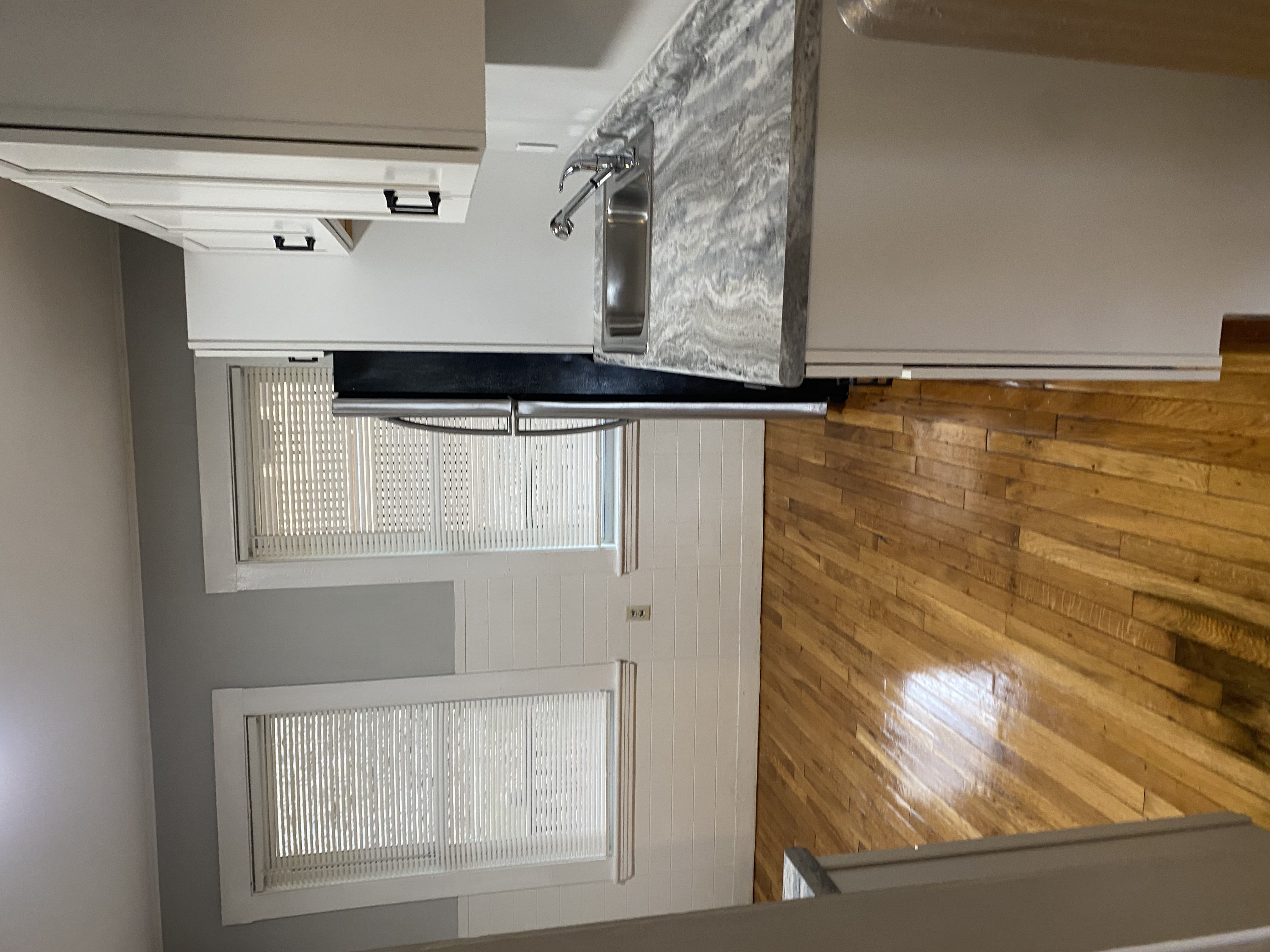 A kitchen with a stainless steel range hood and wooden flooring.