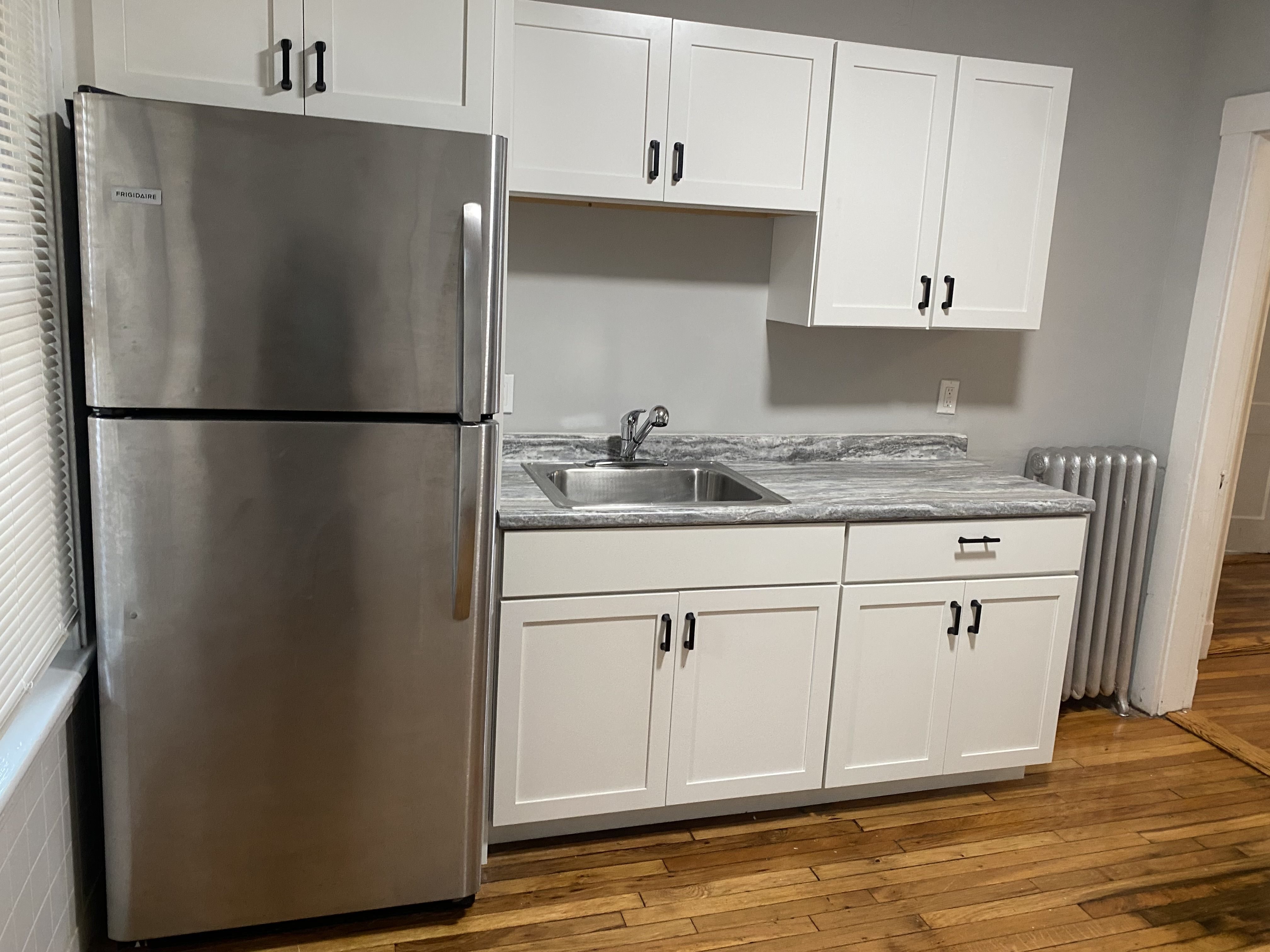 A kitchen with a stainless steel refrigerator and white cabinets.,A kitchen with a stainless steel refrigerator and white cabinets.