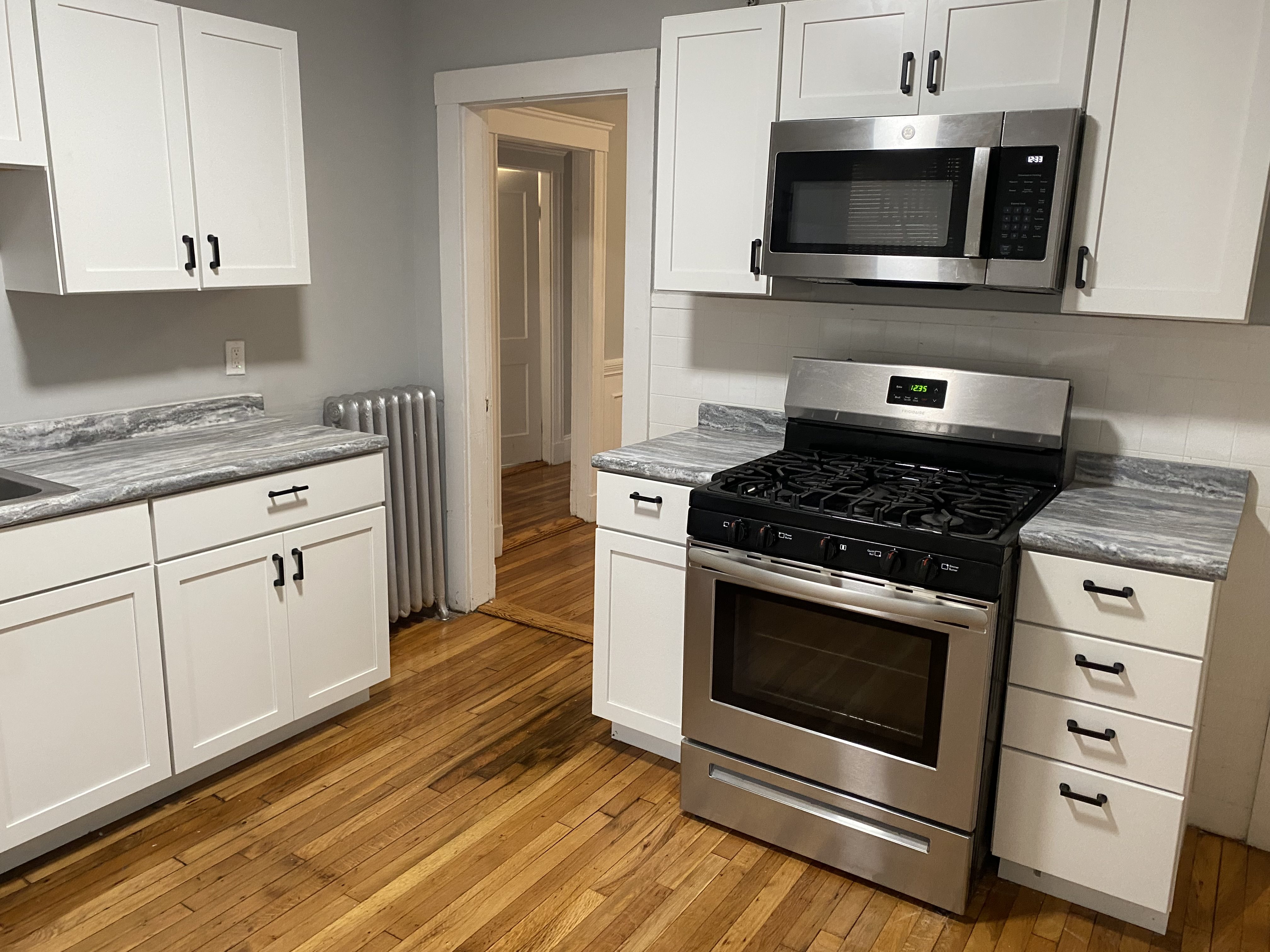 A kitchen with white cabinets and a black stove top oven.