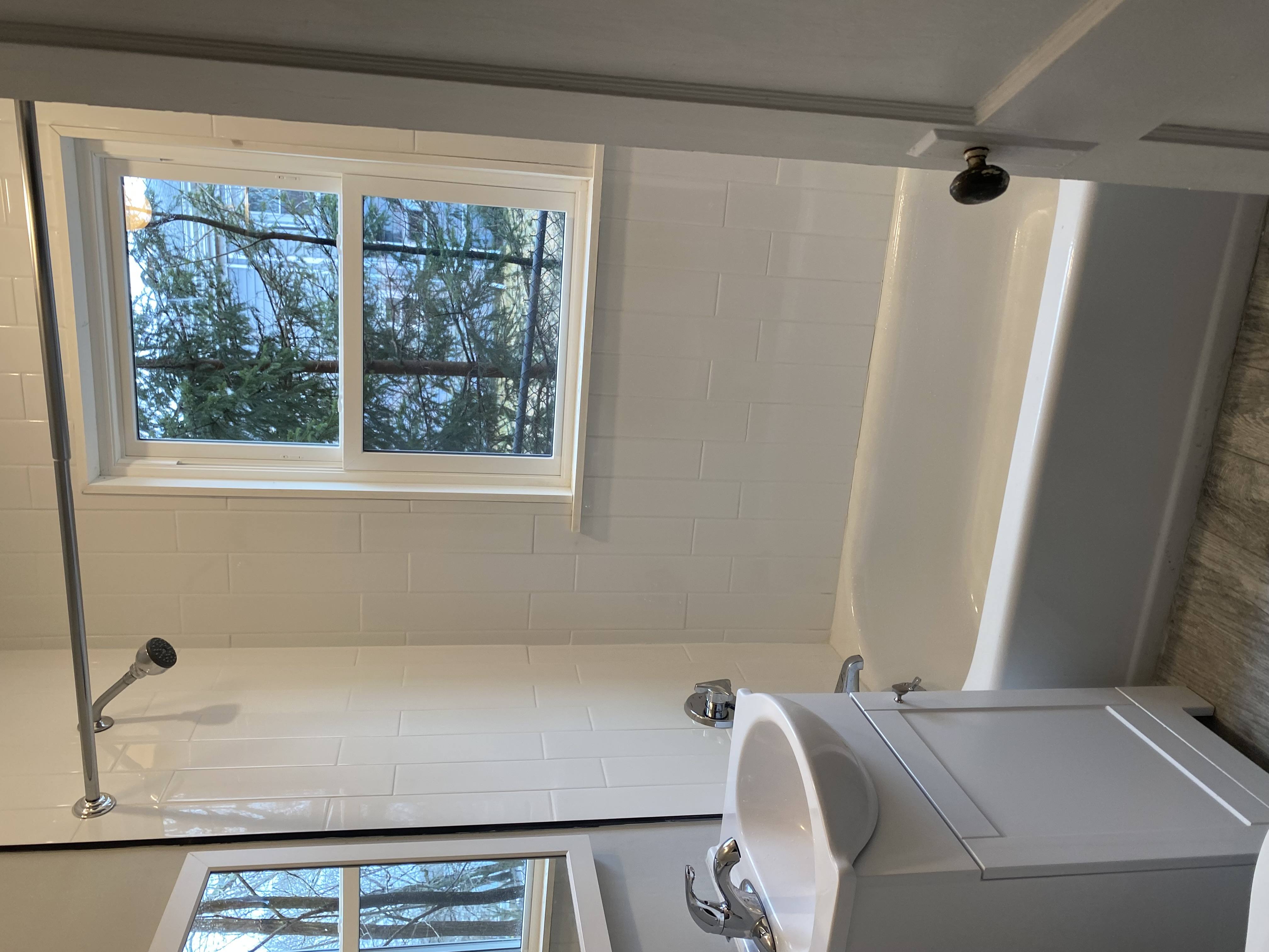 A white bathroom with a window and a sink.
