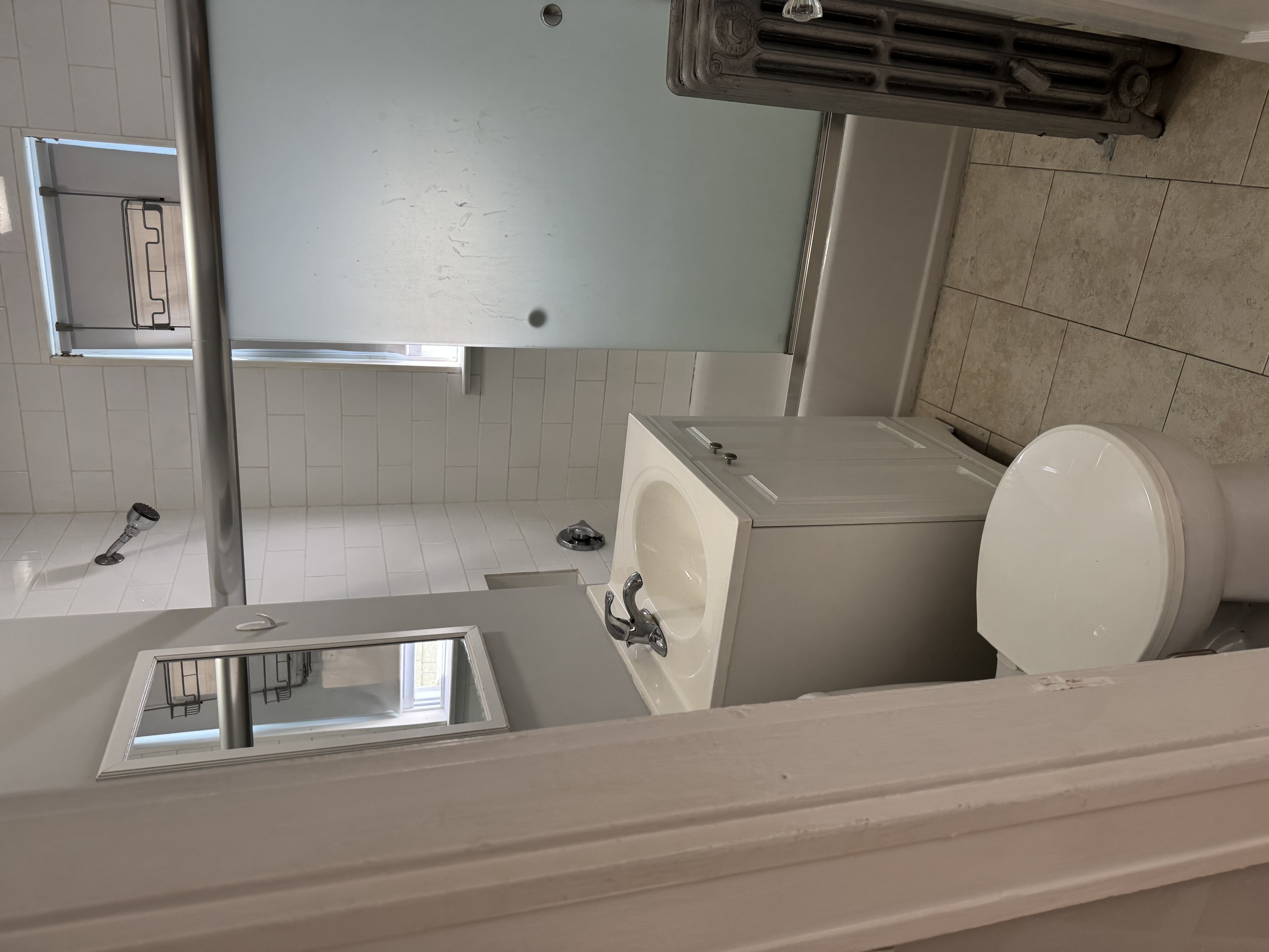 A bathroom with a toilet, sink, and tiled walls.,A bathroom with a toilet, sink, and tiled walls.