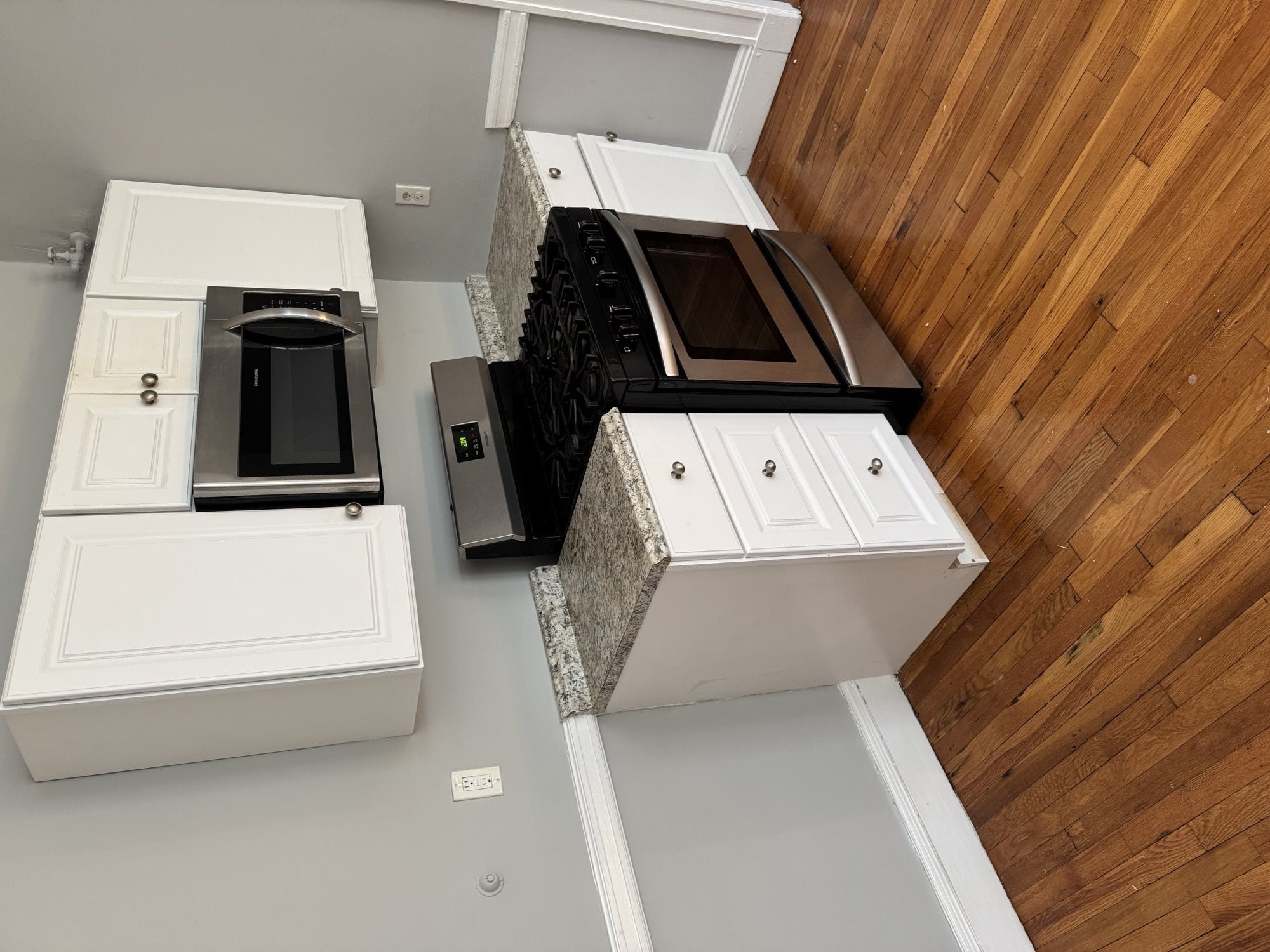 A kitchen with a black oven and white cabinets.