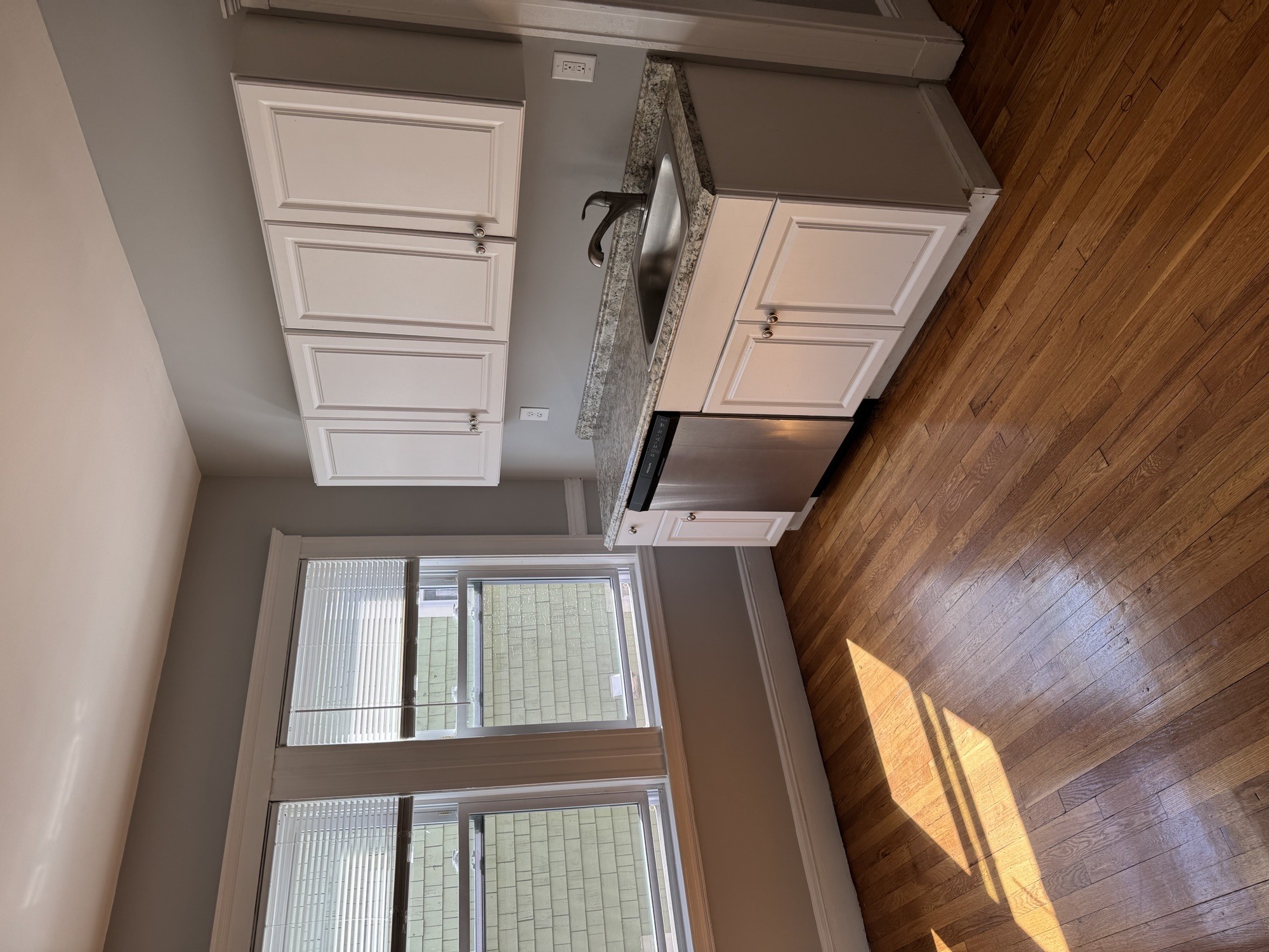 A kitchen with wooden cabinets and a window with blinds.