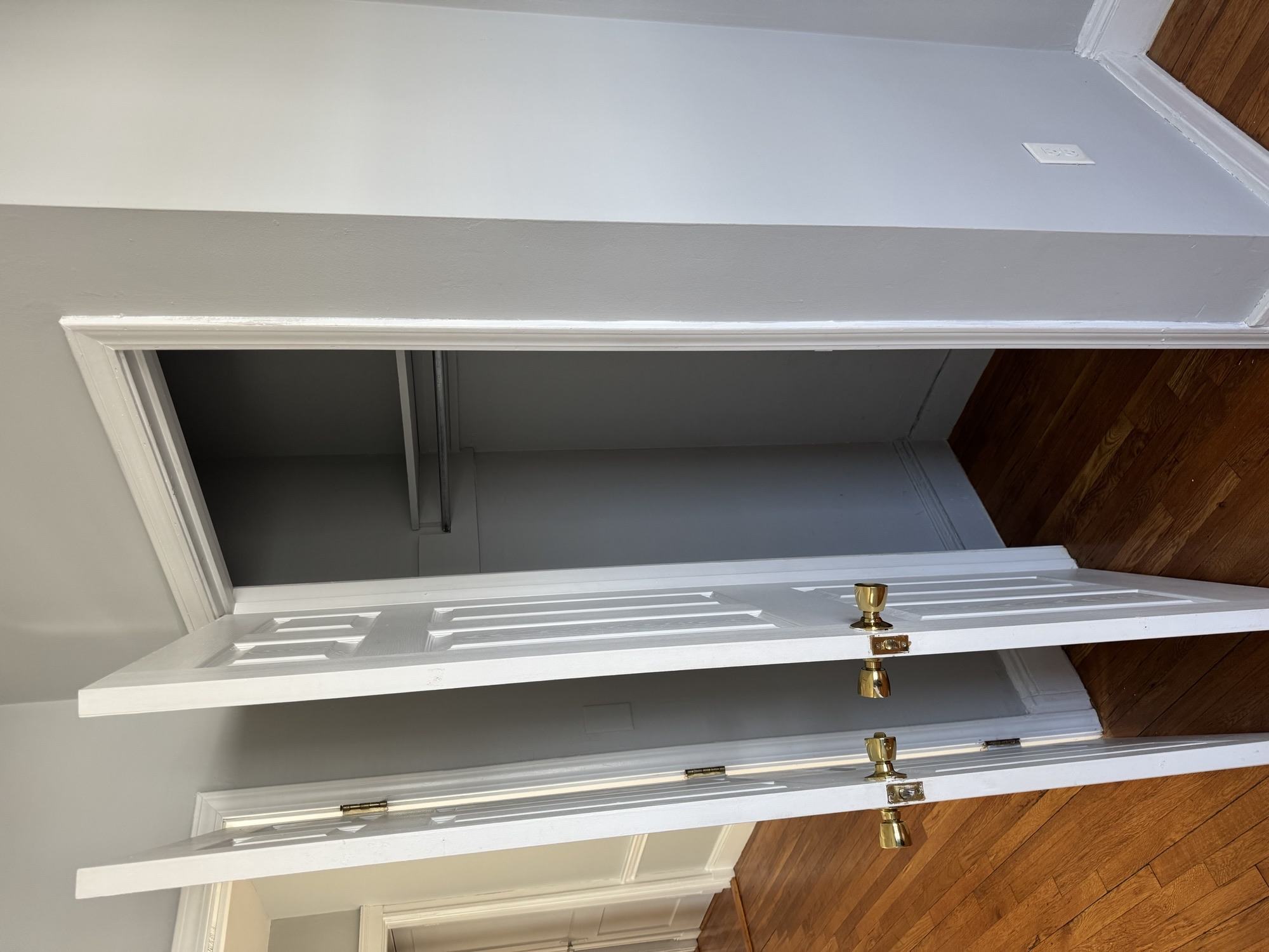 A white shelf with brass fixtures is mounted on a wall.