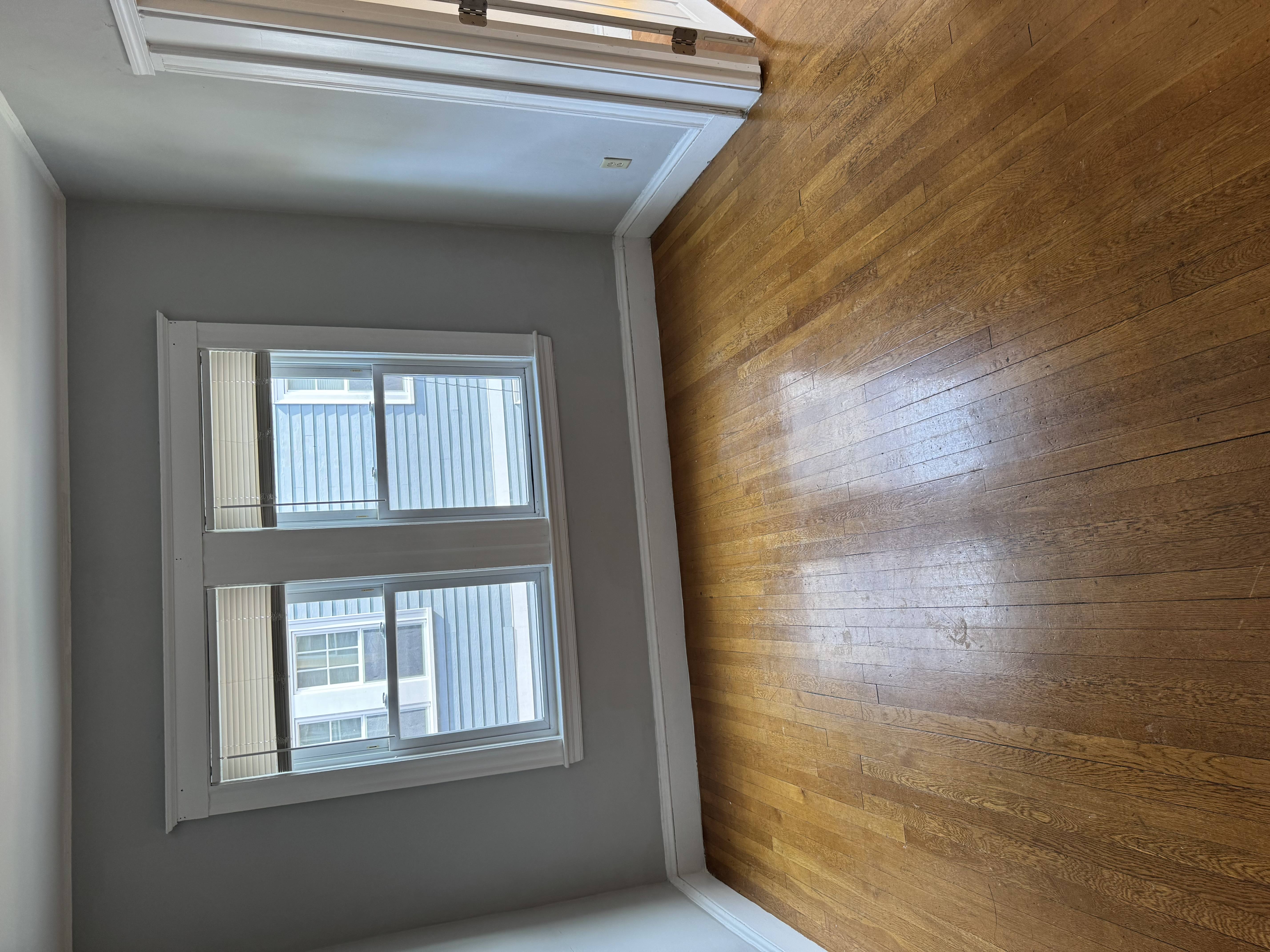 A window with blinds in a room with wooden walls.
