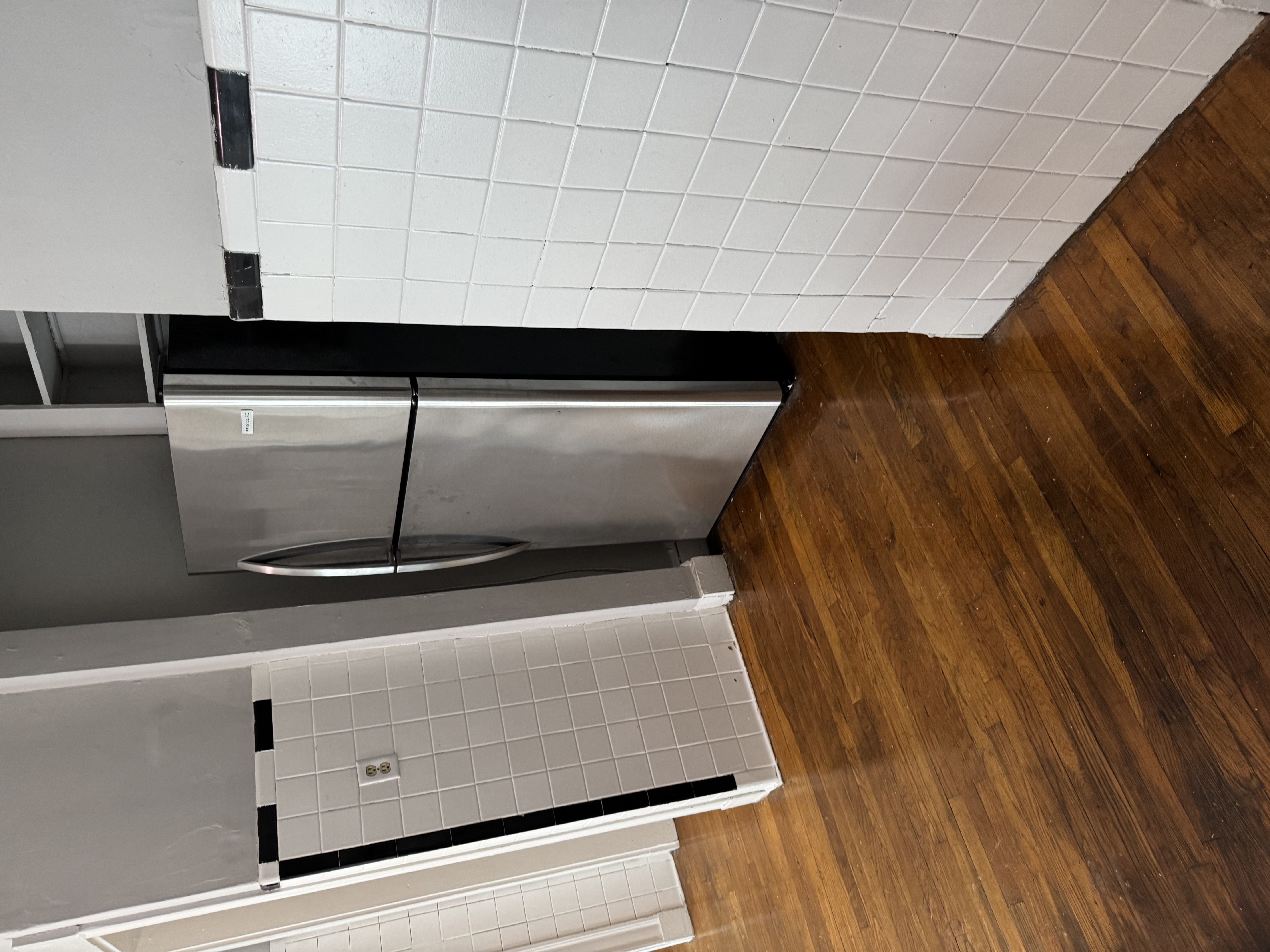 A kitchen with a stainless steel dishwasher and a white tiled floor.