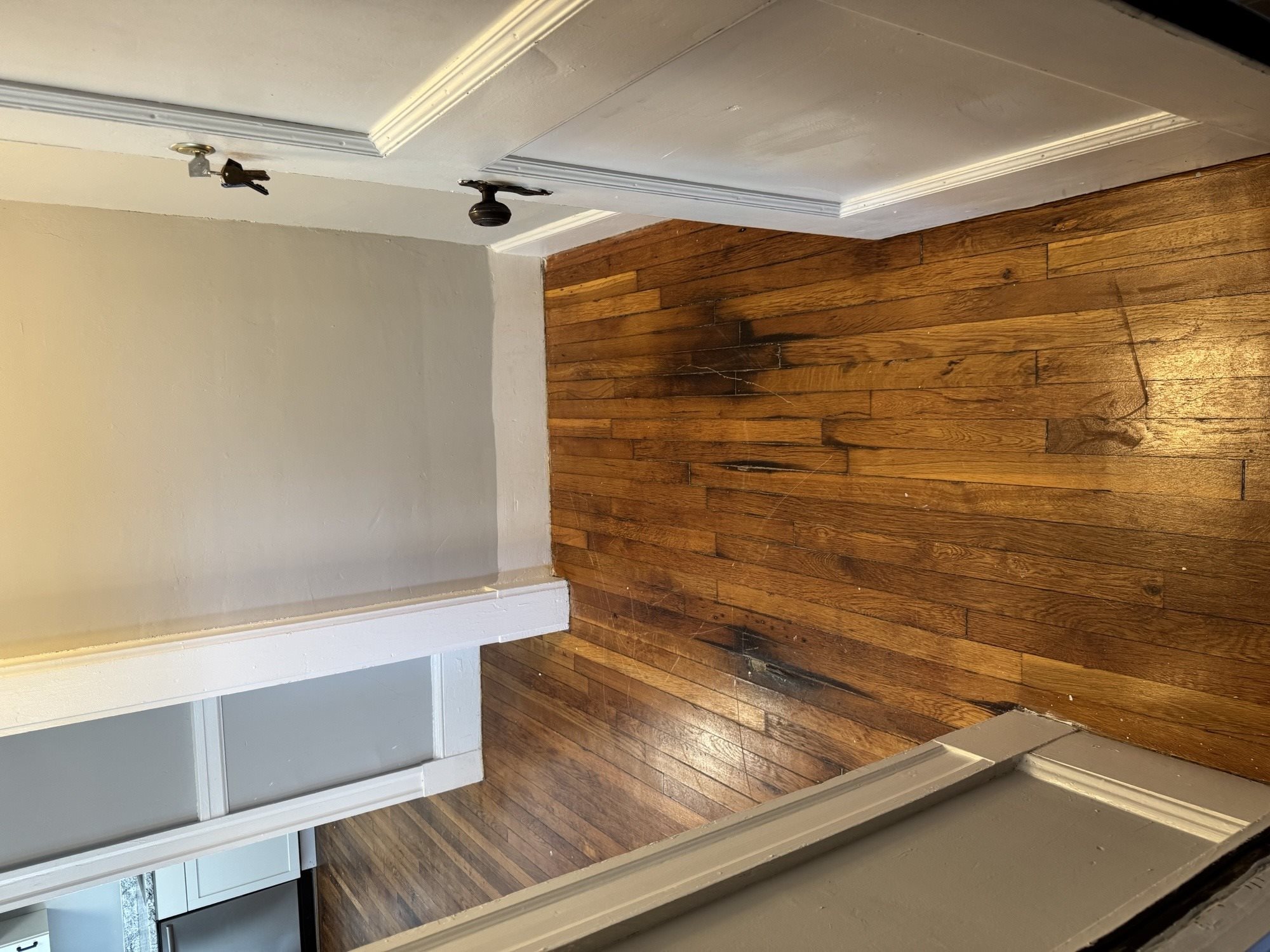 A kitchen with a wooden wall and white cabinets.,A kitchen with a wooden wall and white cabinets.