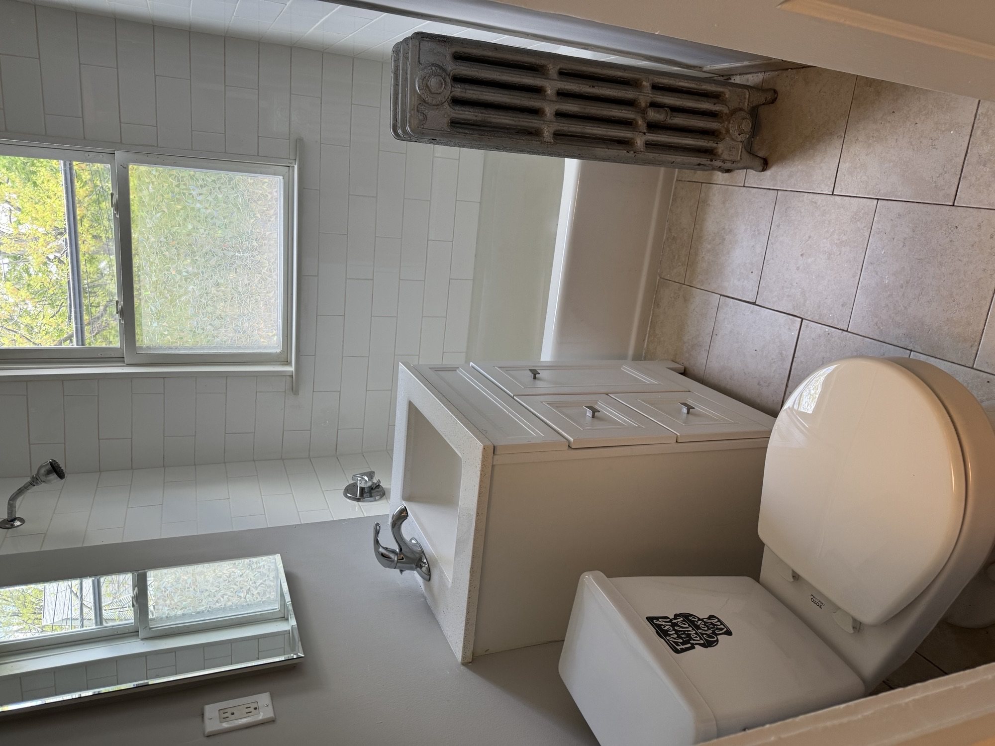 A white toilet with a closed lid is in a bathroom with a window.