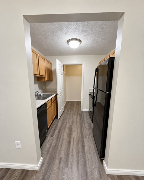 A kitchen with a black refrigerator and wooden cabinets.