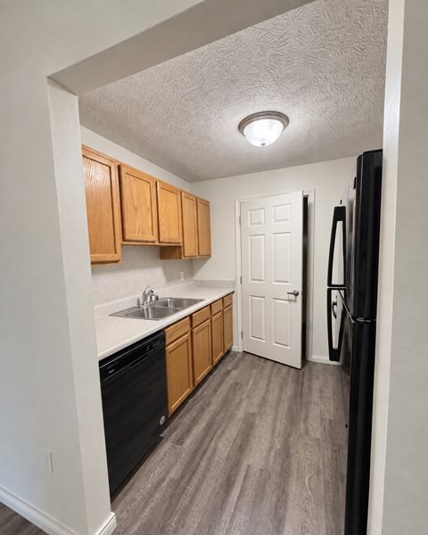A kitchen with wooden cabinets and a black refrigerator.