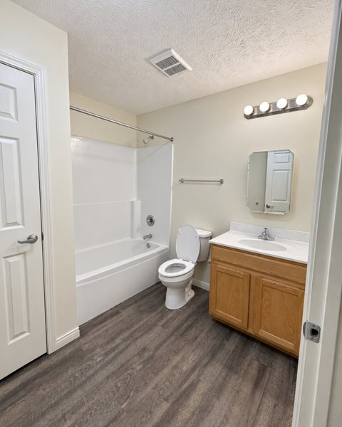 A white toilet sits in a bathroom next to a sink.