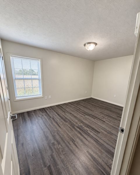 A room with a window and wooden flooring.
