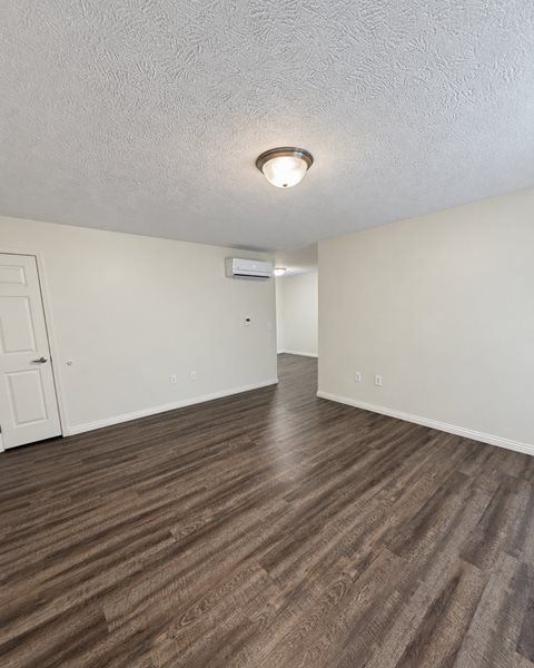 A room with a light on the ceiling and a door on the left.