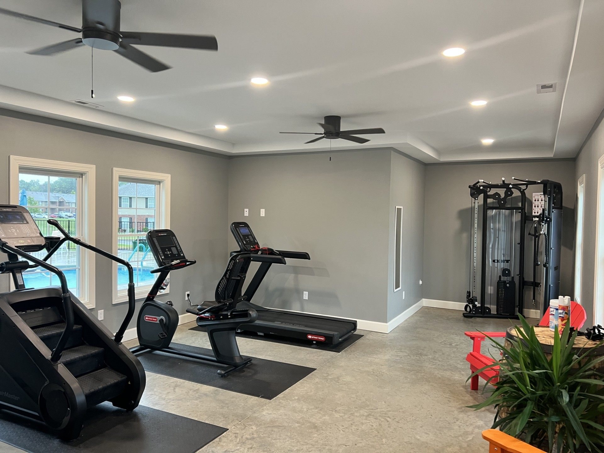 A home gym with treadmills, elliptical machines, a stair stepper and a cable machine.