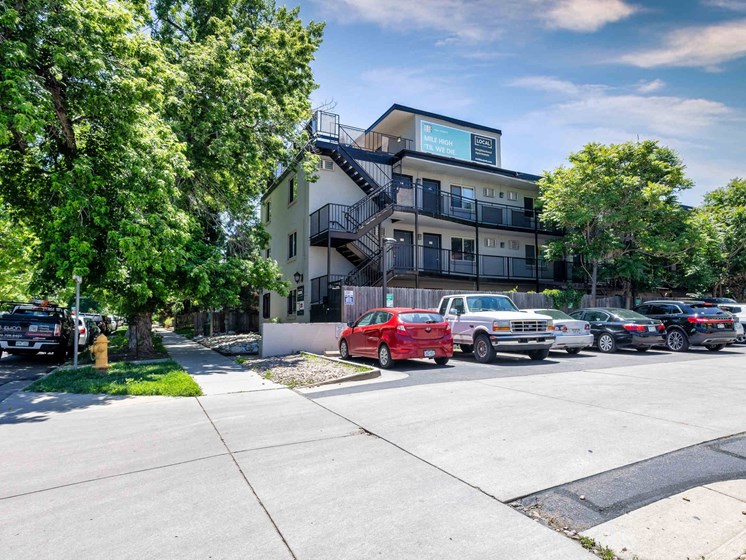 Full view of modern apartment complex with tree-lined street, parking area, and updated exterior design at 1443 Elizabeth in Denver, CO