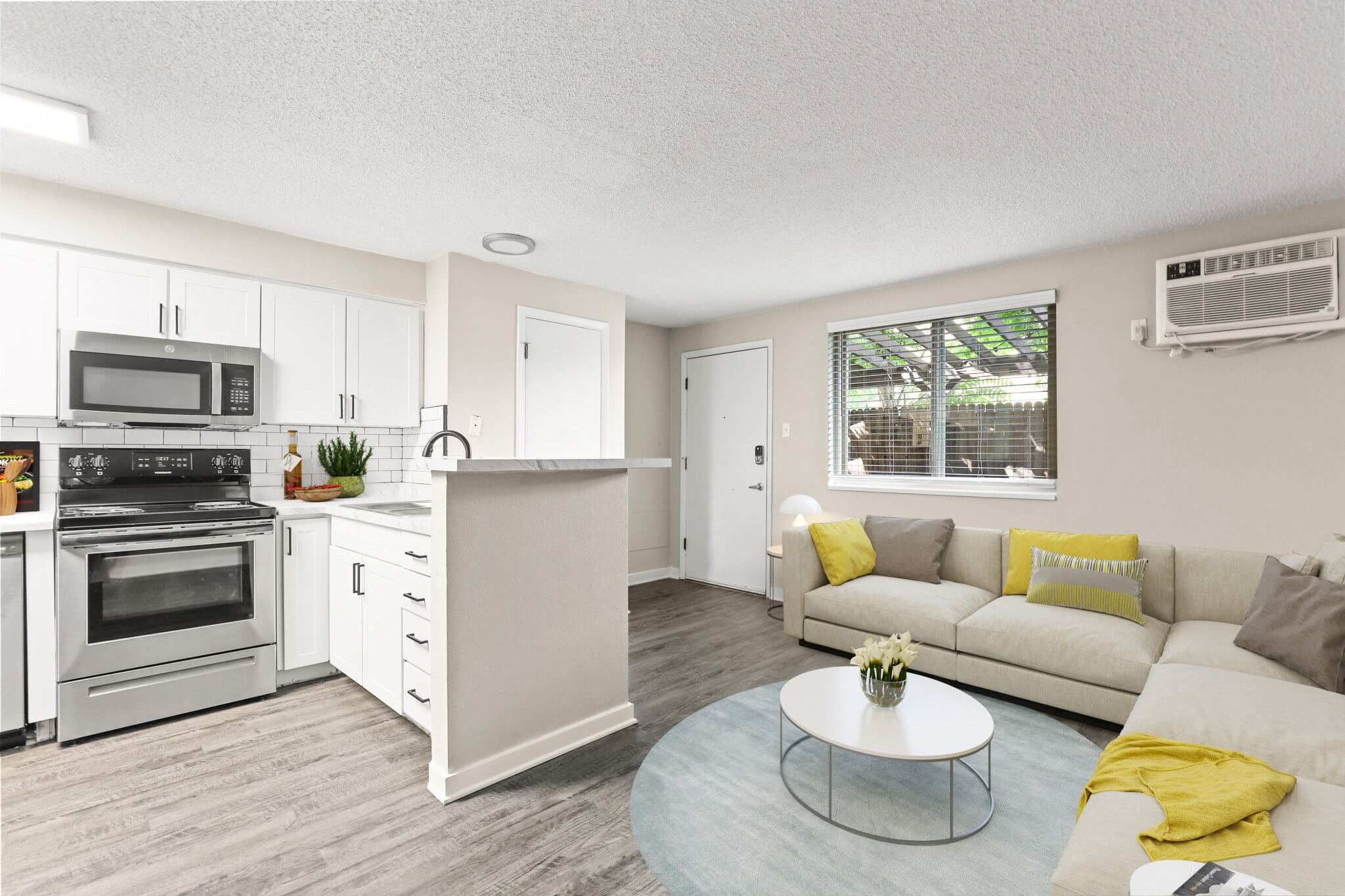 Spacious living room with sectional sofa, large window, air conditioning unit, and full kitchen in view at 1443 Elizabeth in Denver, CO