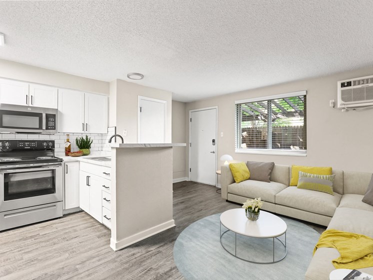 Spacious living room with sectional sofa, large window, air conditioning unit, and full kitchen in view at 1443 Elizabeth in Denver, CO