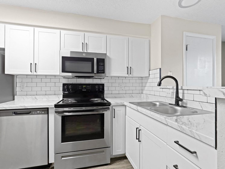 Fully updated kitchen with white shaker cabinets, subway tile backsplash, black fixtures, and stainless steel appliances at 1443 Elizabeth in Denver, CO