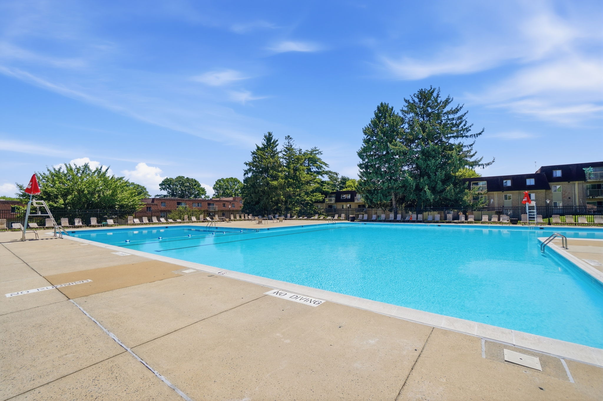 A large swimming pool with a blue water surface and a red flag in the background.