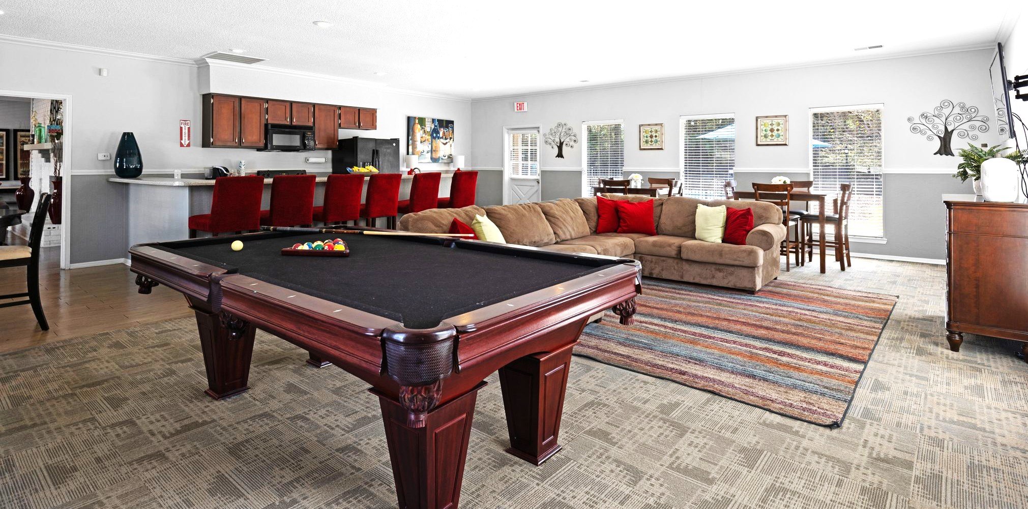 A pool table is in the middle of a room with a couch and a rug.