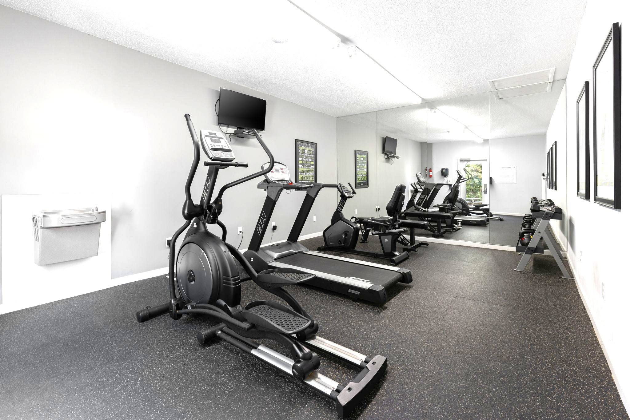 A gym with treadmills, elliptical machines, and a stationary bike.