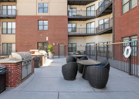 A patio with a table and chairs is surrounded by a brick building.