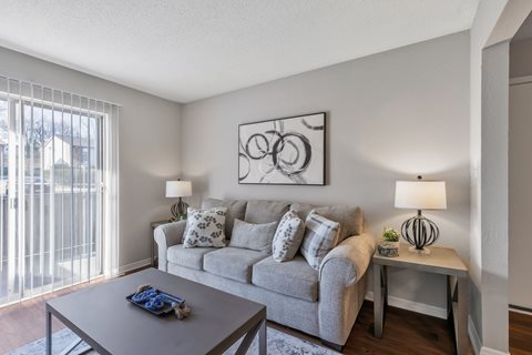 A living room with a grey couch, a coffee table, and a painting on the wall.