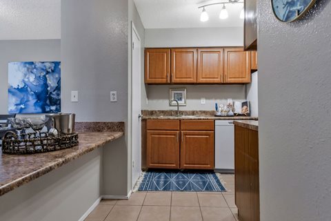 A kitchen with brown cabinets and a blue rug on the floor.