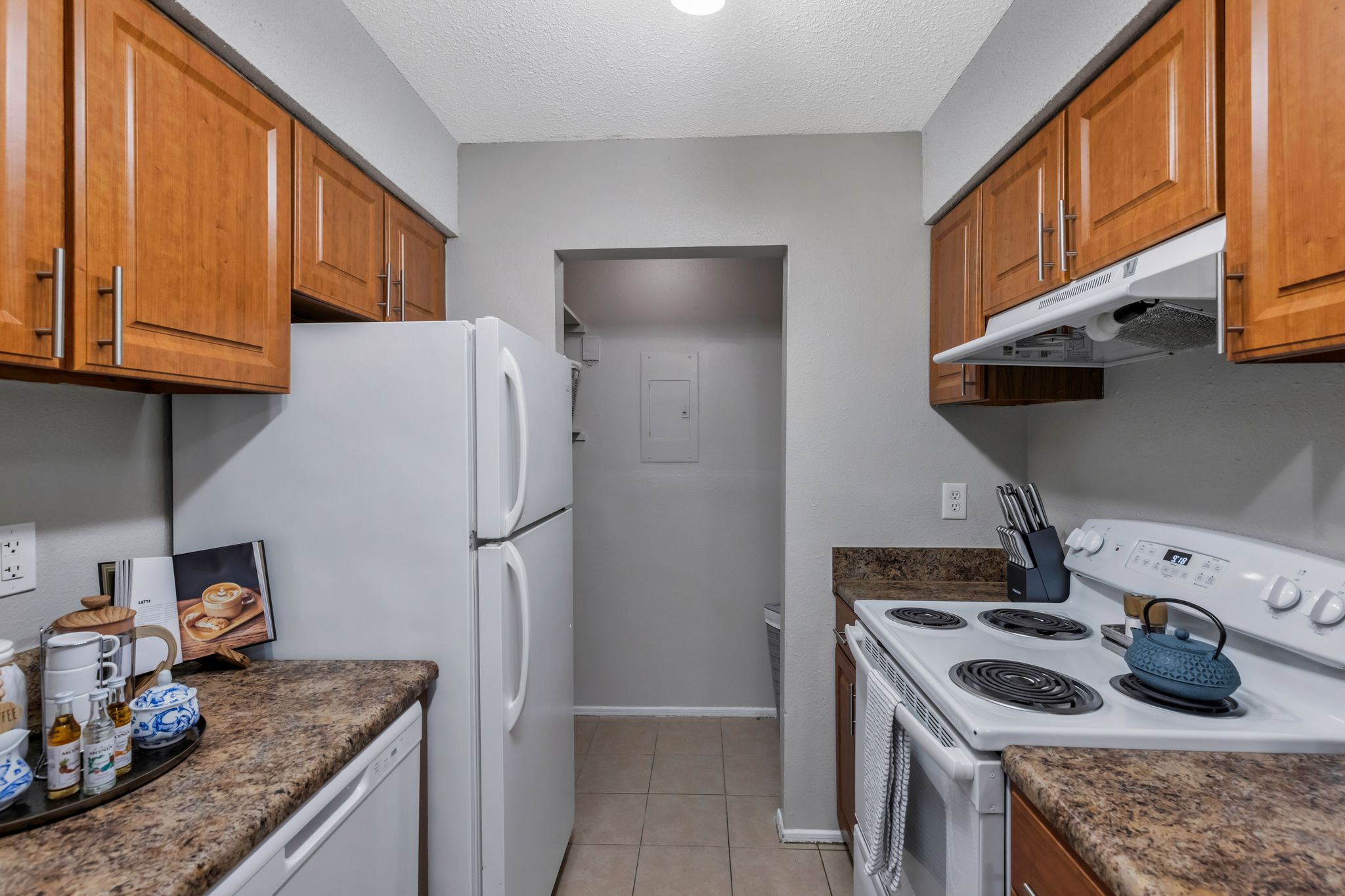 A kitchen with a white refrigerator, white stove, and brown cabinets.