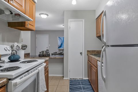 A kitchen with a white stove top oven and a white refrigerator.