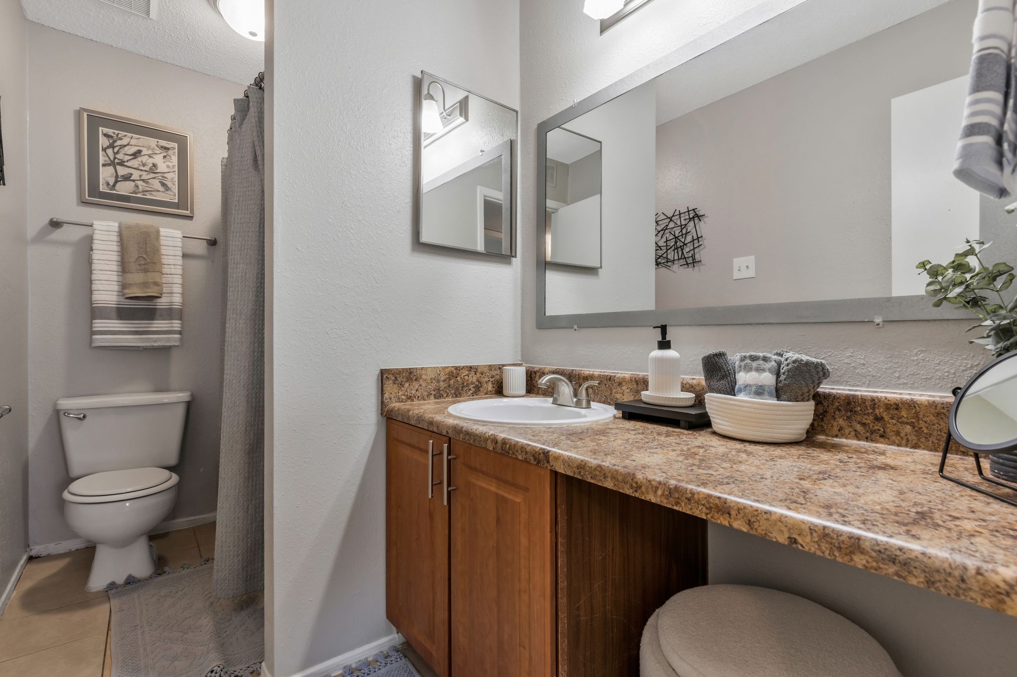 A bathroom with a toilet, sink, and mirror.