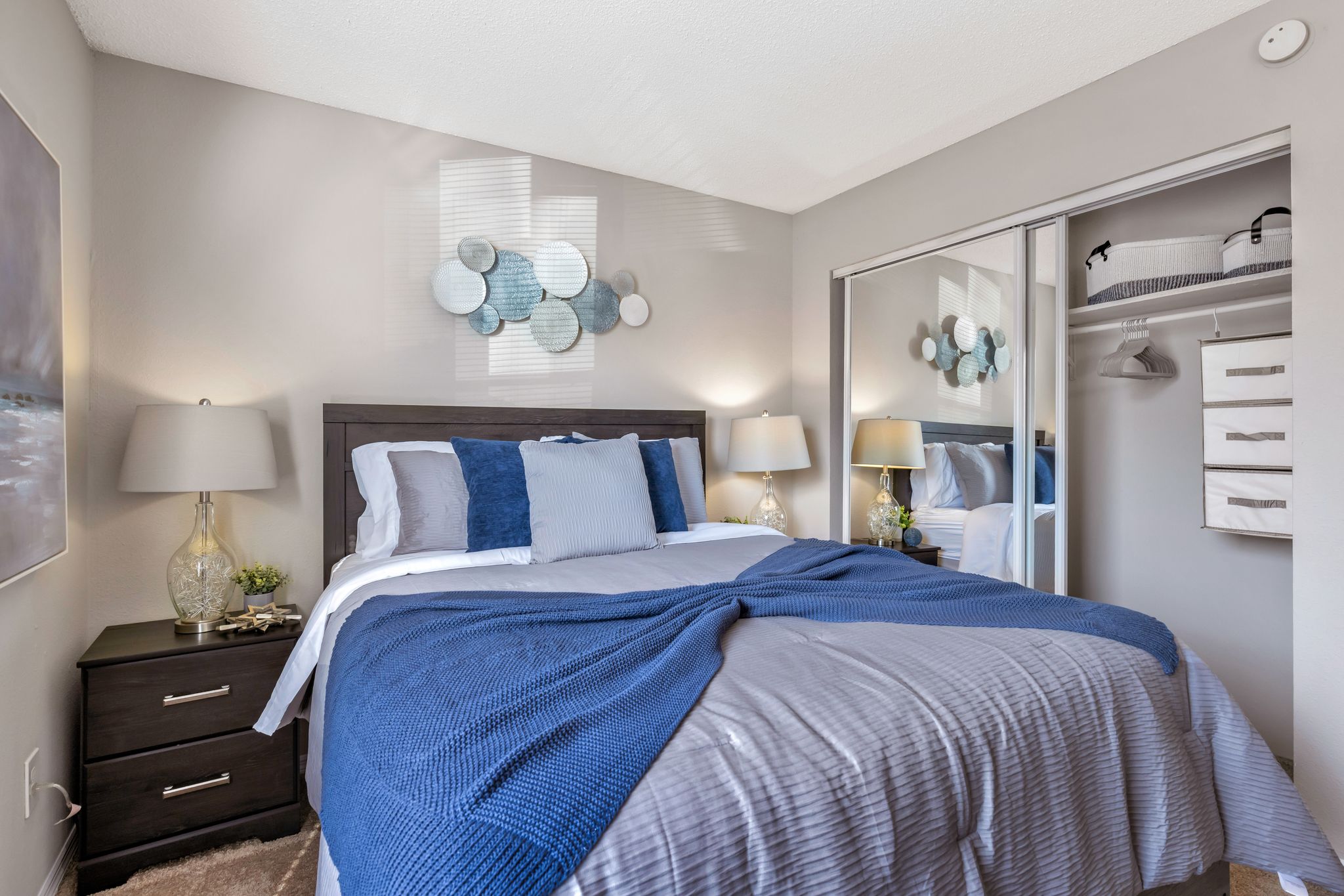 A bedroom with a bed covered in a blue and white striped comforter.