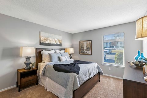 A bedroom with a bed, nightstand, and a painting on the wall.