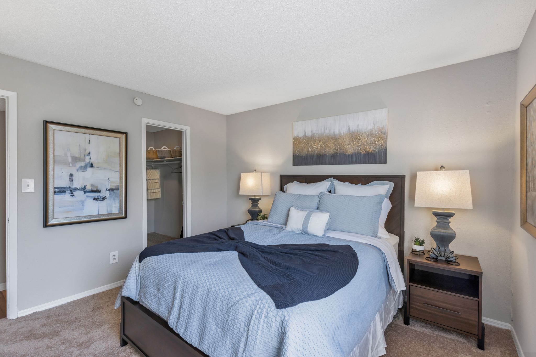 A bedroom with a bed, nightstands, and pictures on the wall.