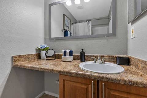 A bathroom with a granite countertop and a round mirror.