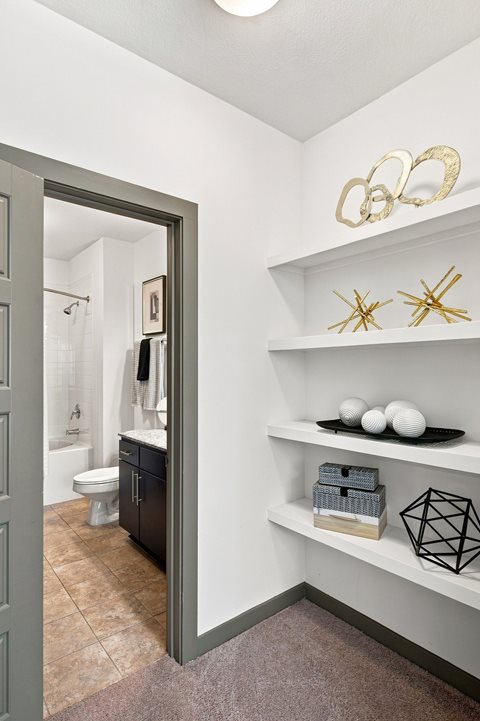 A bathroom with a toilet, sink, and a shelf with decorative items.