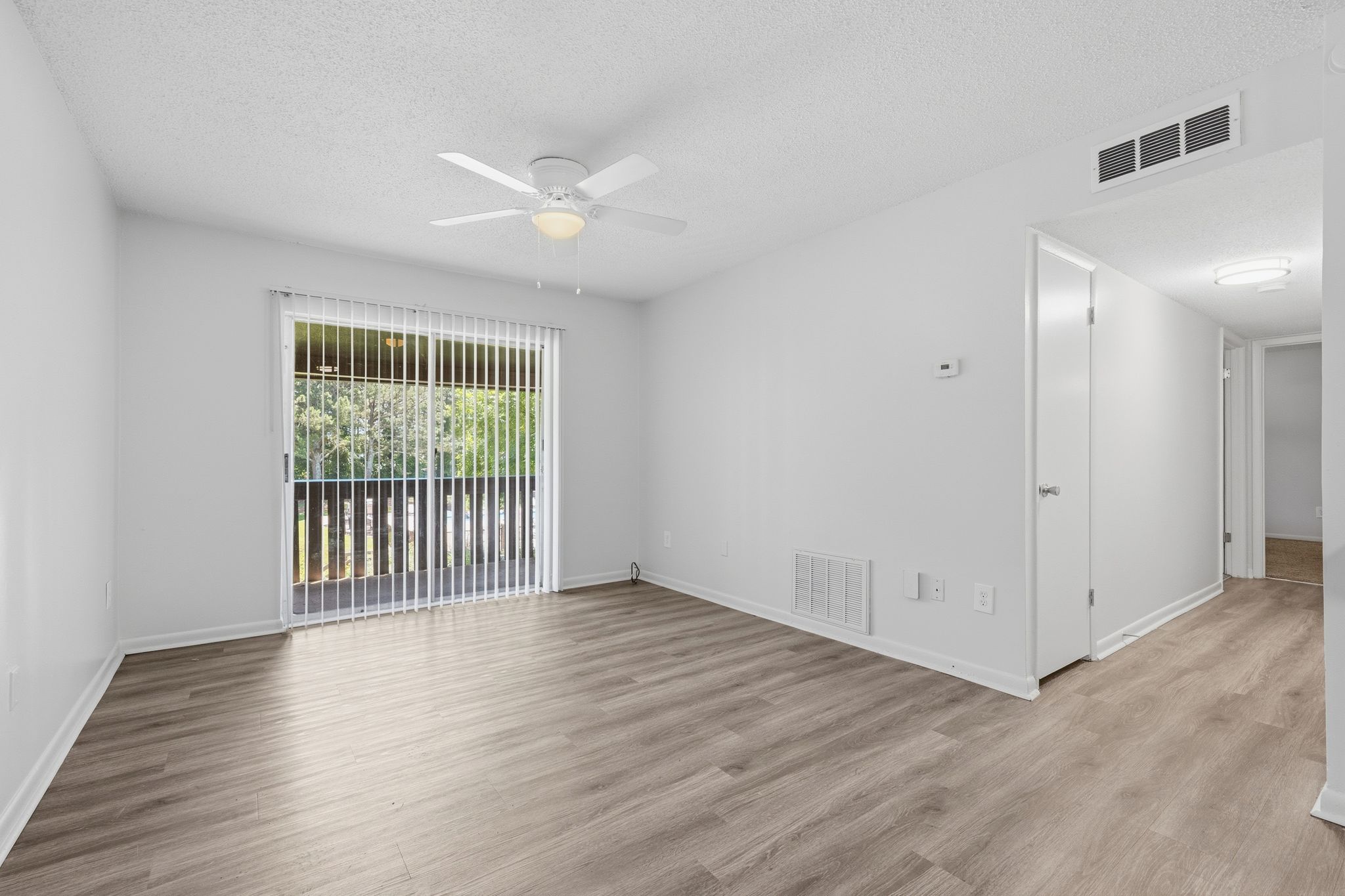 A room with a ceiling fan and a window with blinds.