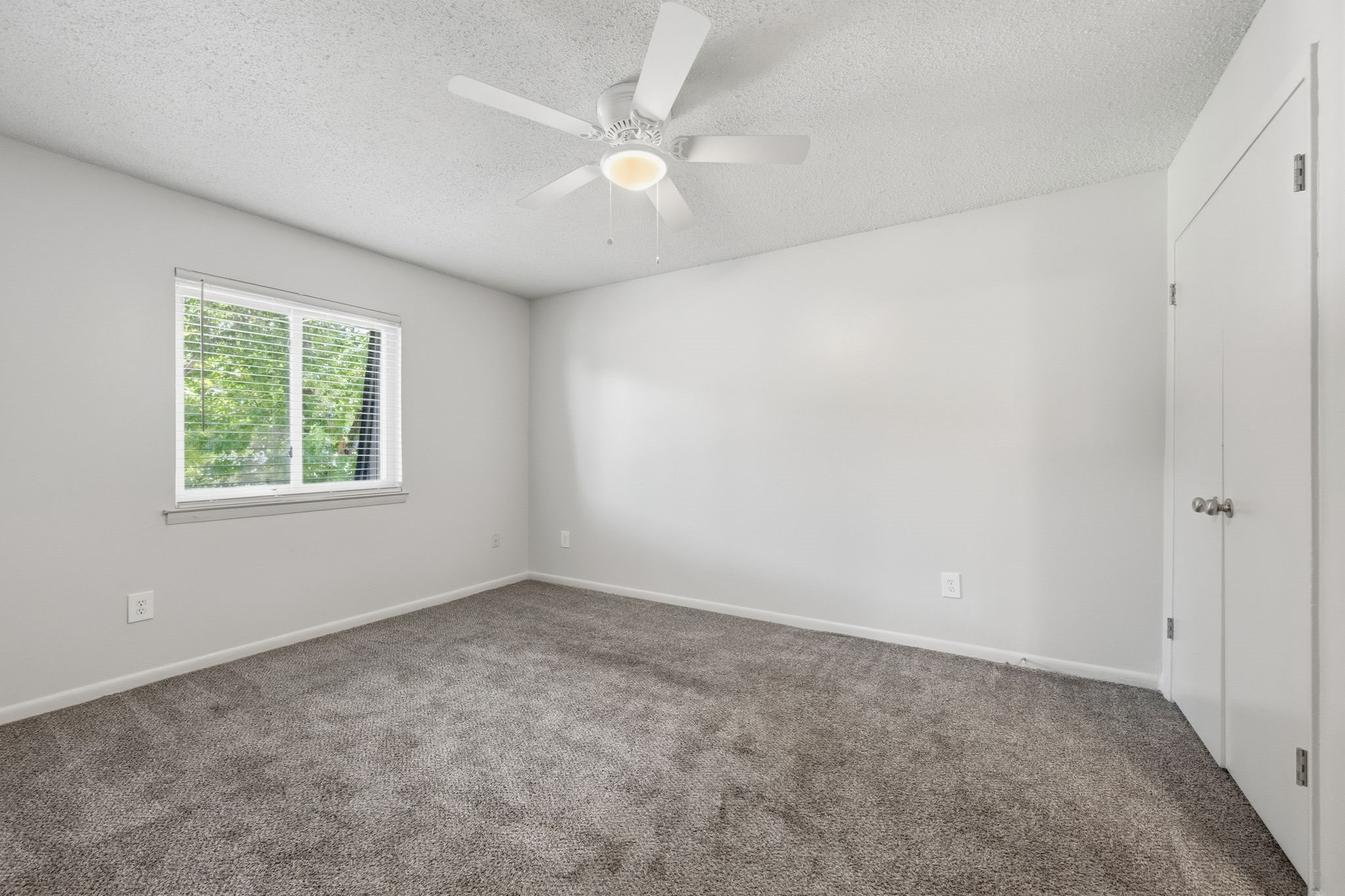 A room with a ceiling fan and a window.