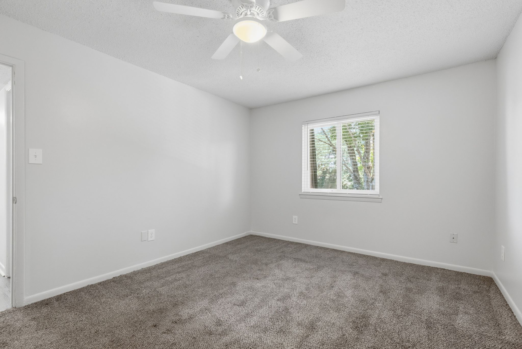 A room with a ceiling fan and a window.
