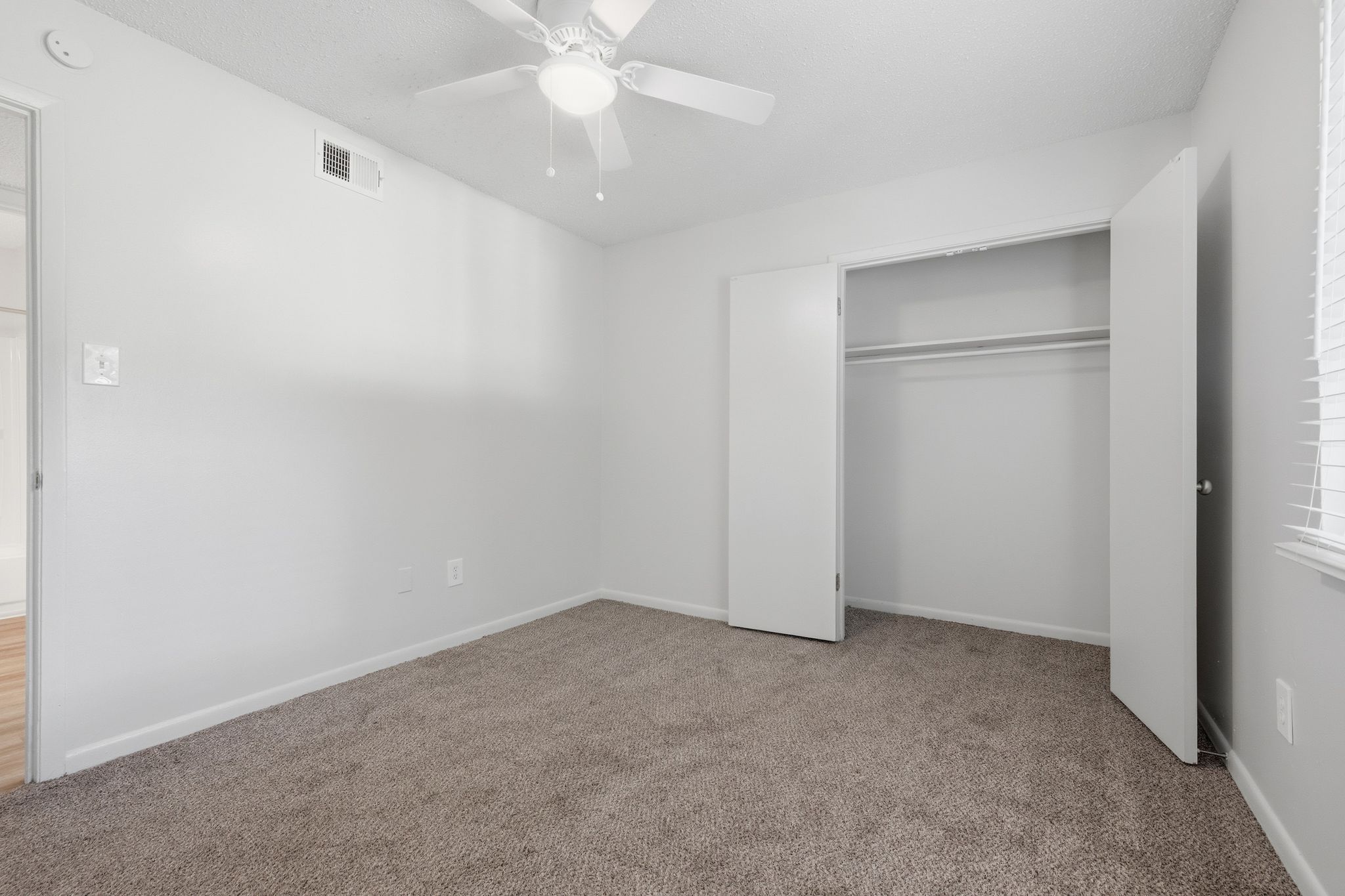 A room with a ceiling fan and carpeted floor.