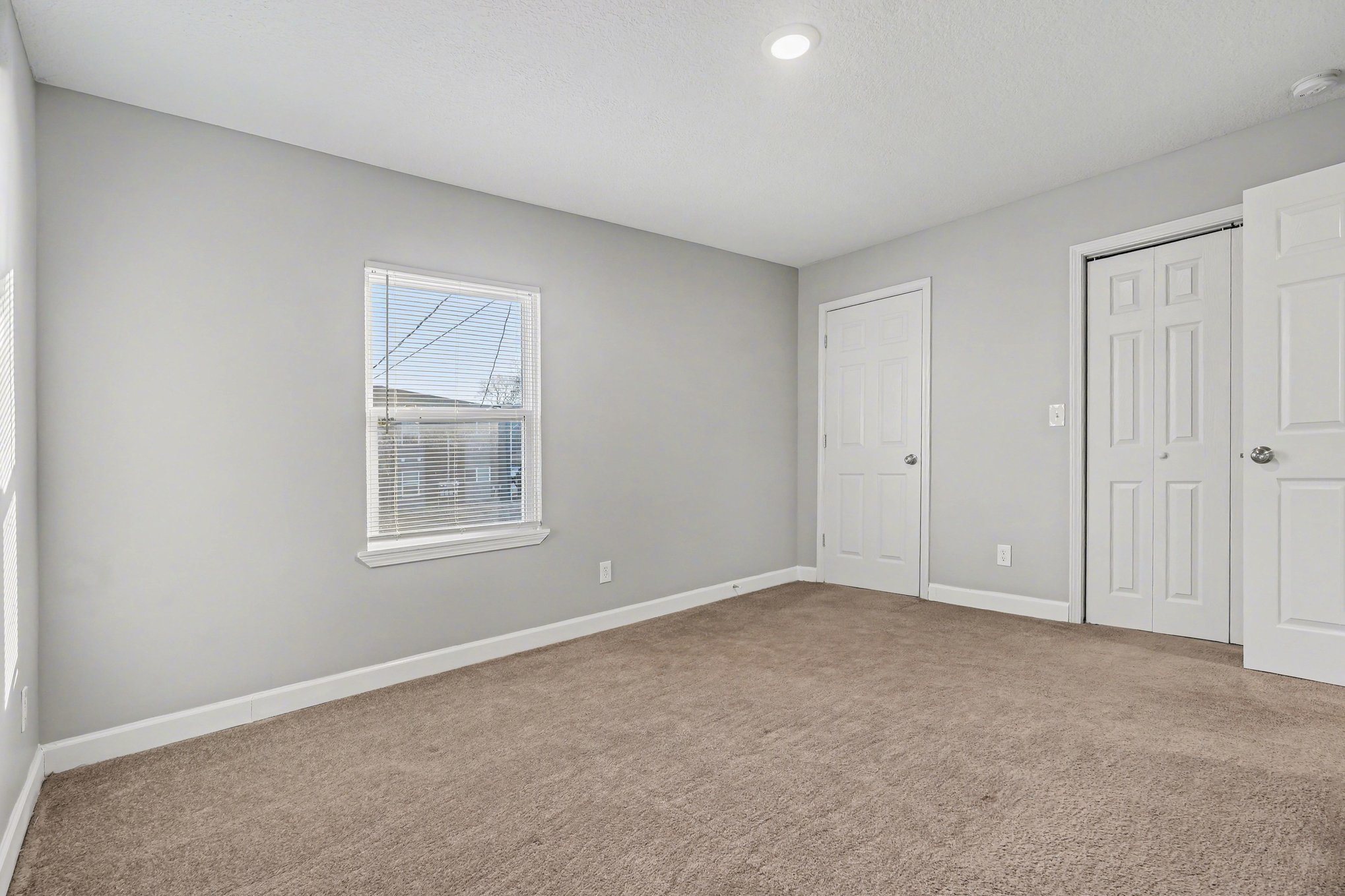 A room with a carpeted floor and two doors.