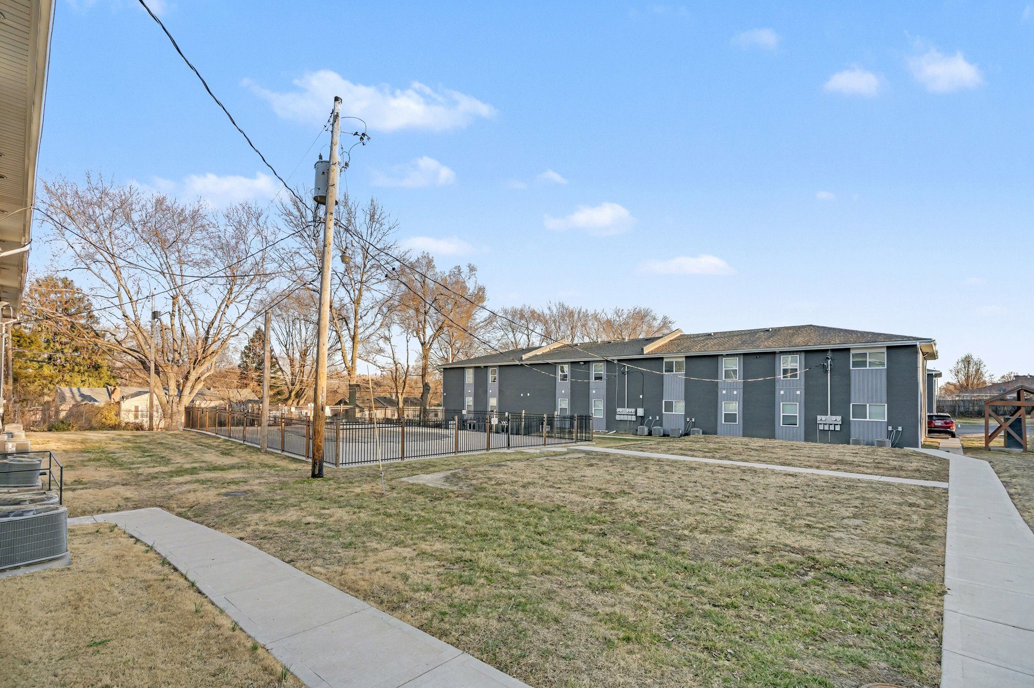 A long building with a grey roof is surrounded by a fence.