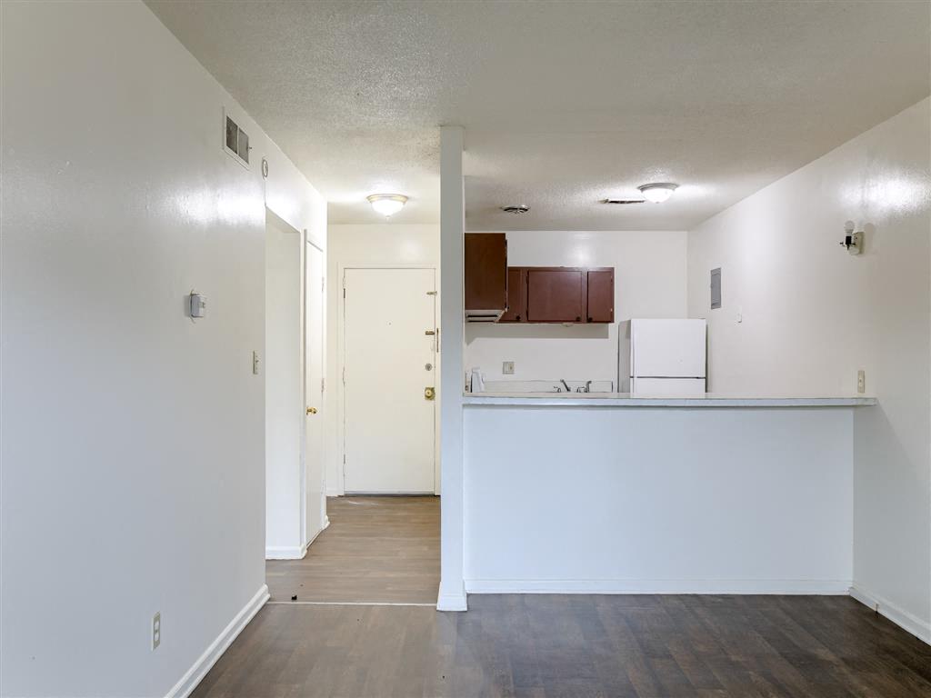 an empty living room and kitchen with white walls and wood floors