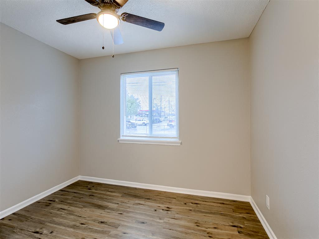an empty bedroom with a ceiling fan and a window
