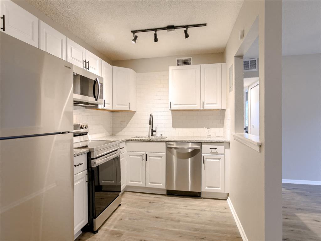 an empty kitchen with white cabinets and stainless steel appliances