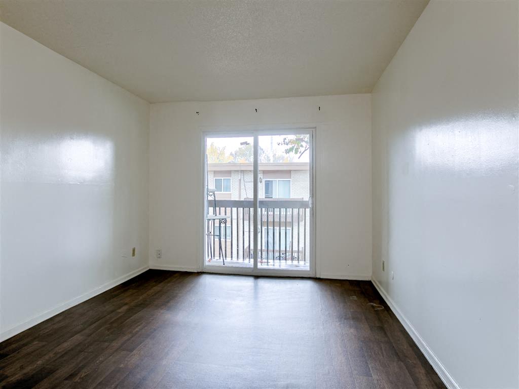 the living room of an empty apartment with wood floors and a balcony