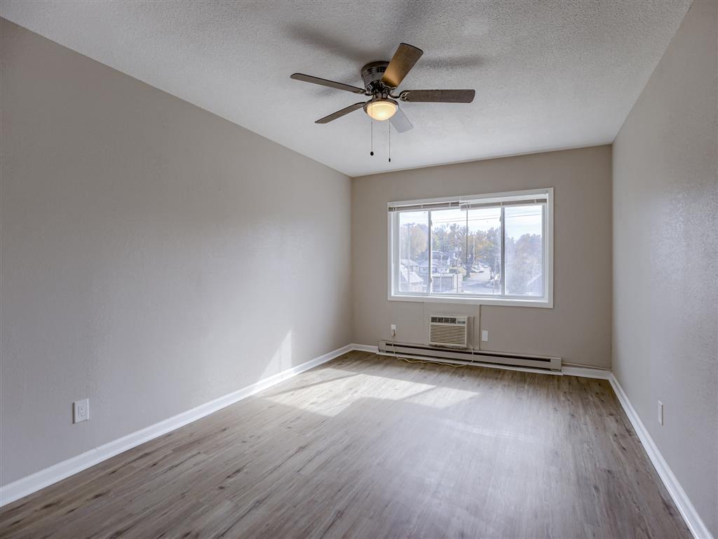 an empty living room with a ceiling fan and a window